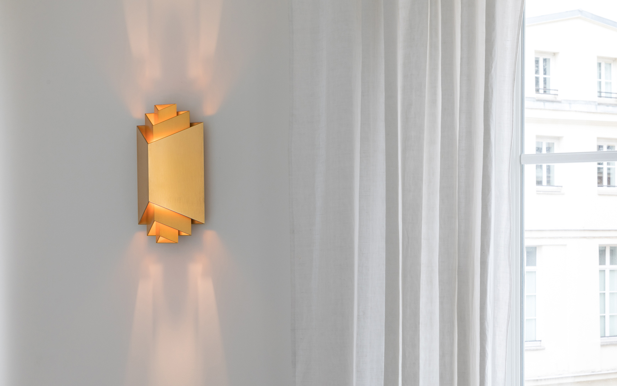Wandleuchte „Gélule“ von Joseph Dirand neben einem großen Fenster