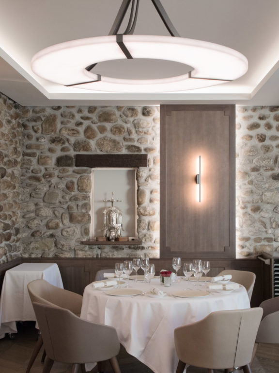 Kronleuchter Luxembourg und Wandleuchte Untitled A in einem Restaurantraum mit Steinwänden