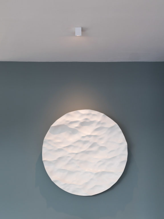 The Marienbad S55 spotlight by Gounot & Jähnke illuminates a white sculpture on a teal blue wall