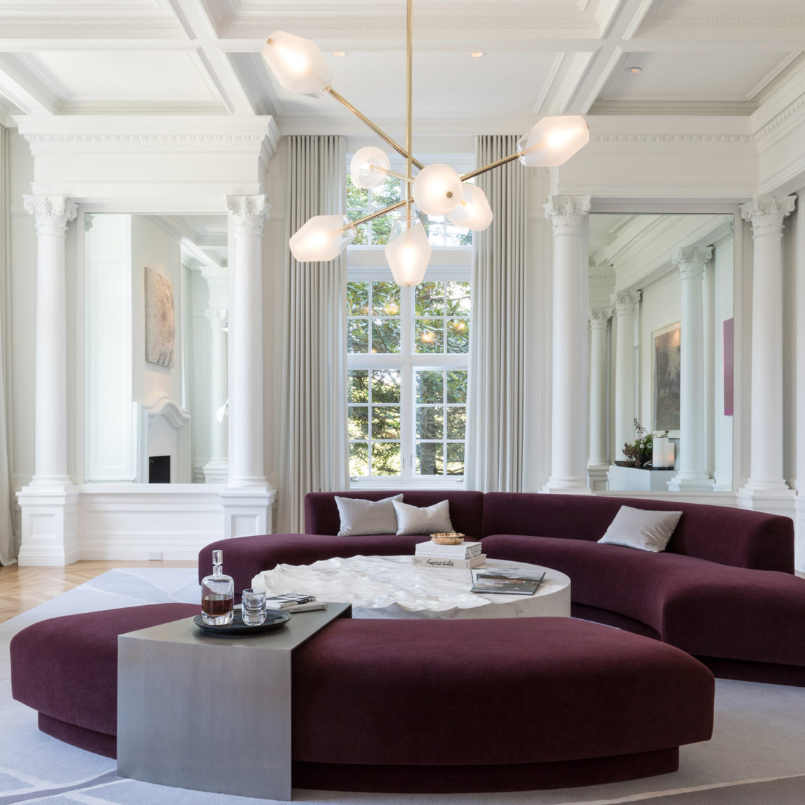 Régis Botta's Opéra chandelier illuminates a large living room with a burgundy sofa