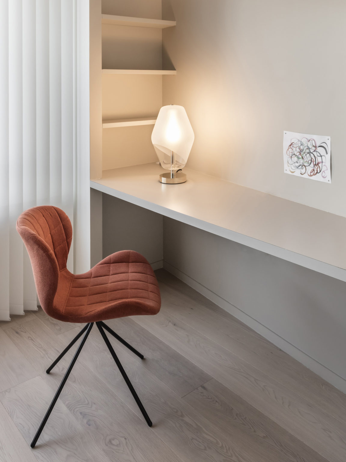 Régis Botta's Saint-Germain table lamp on a white table facing a rust-colored chair