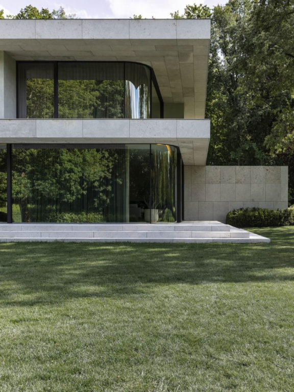 Große Villa mit großen Fenstern, umgeben von Bäumen