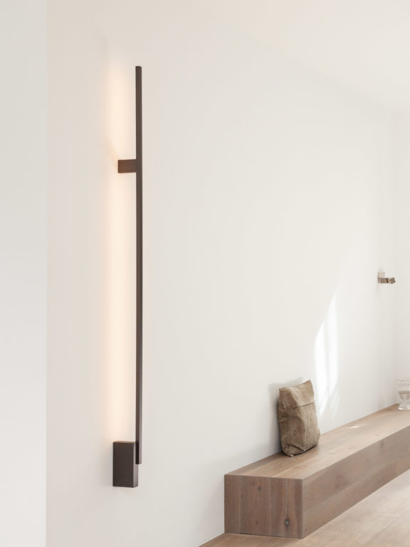 La lumière de l'applique Untitled H illumine indirectement un couloir blanc
