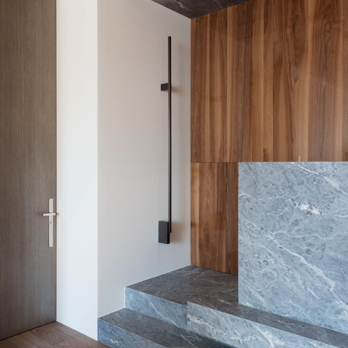L'applique discrète Untitled H prend place dans un salle en bois, marbre et plâtre blanc