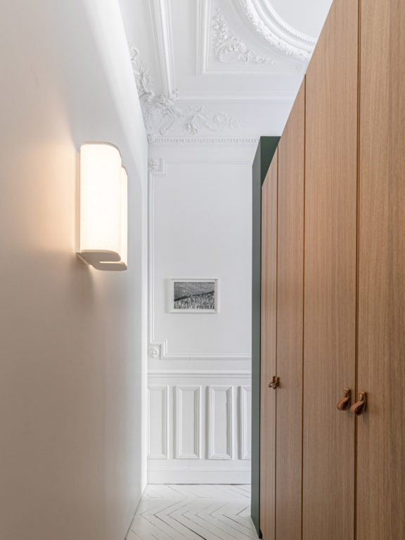 The Brasilia A sconce illuminate a hallway with wooden cupboards