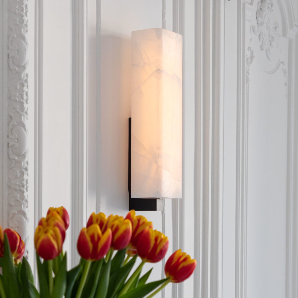 Wandleuchte Embrun A Ozone in einer Pariser Wohnung mit einem Strauß roter und gelber Tulpen