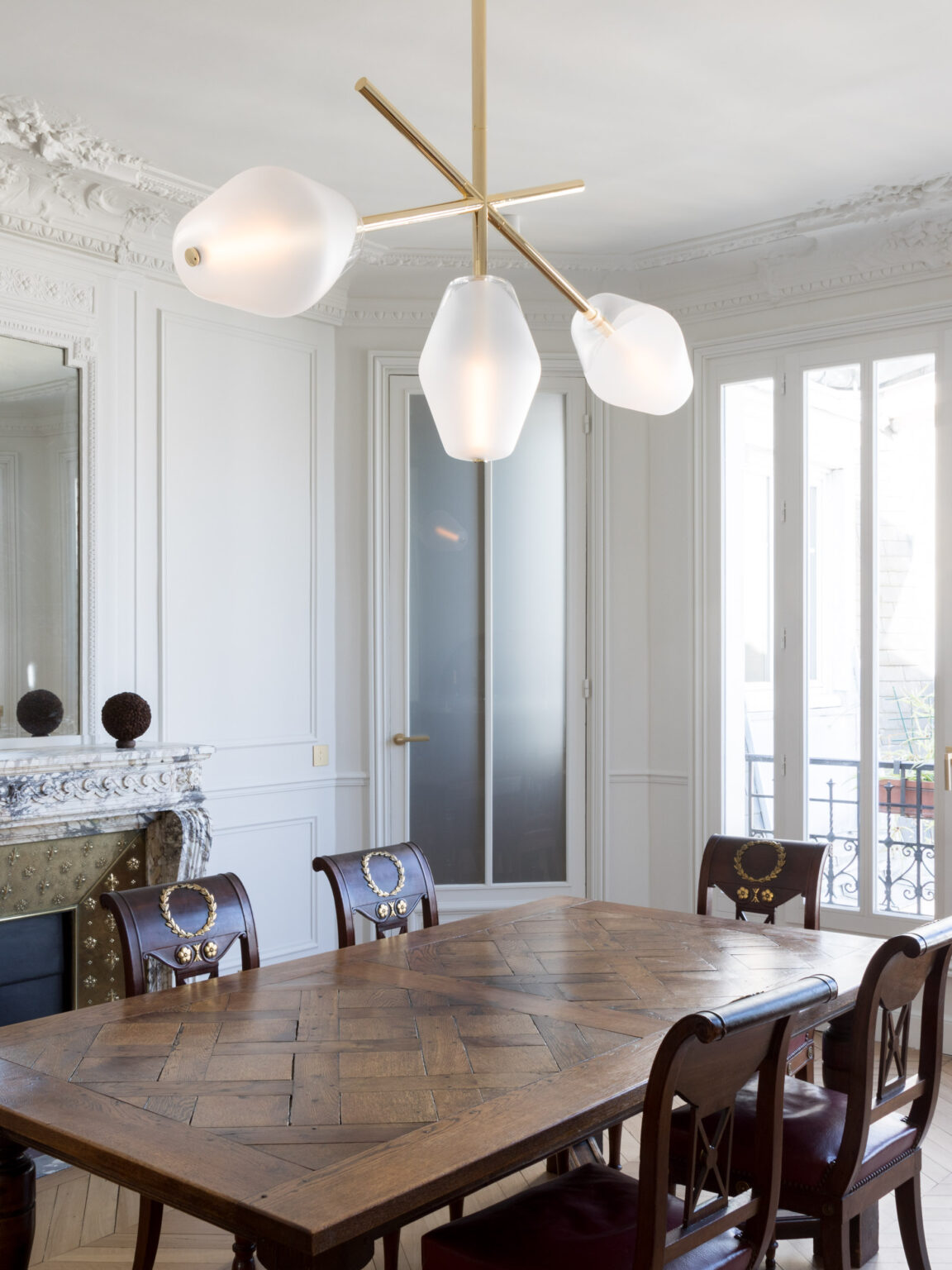 Concorde pendant light by Régis Botta hangs above a vintage wooden table