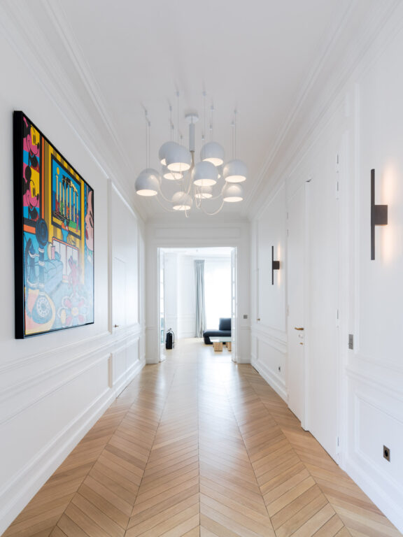 The Untitled A sconces and the Paulin M101 chandelier with its 12 globes in a long hallway