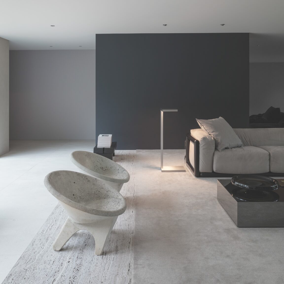 Die Stehleuchte Furtiv LH Ozone beleuchtet das Wohnzimmer eines minimalistischen grauen Hauses.