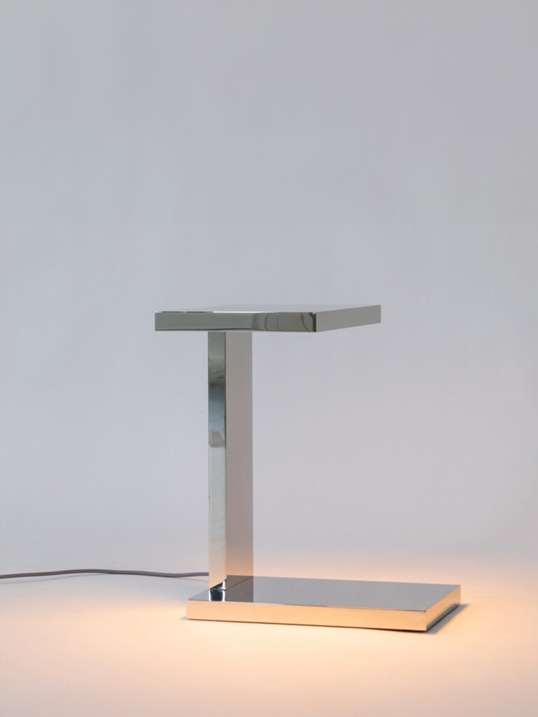 La lampe à poser Furtiv LP de Lauriot-Prévost et Perrault en nickel miroir illumine le décor blanc dans lequel elle se trouve