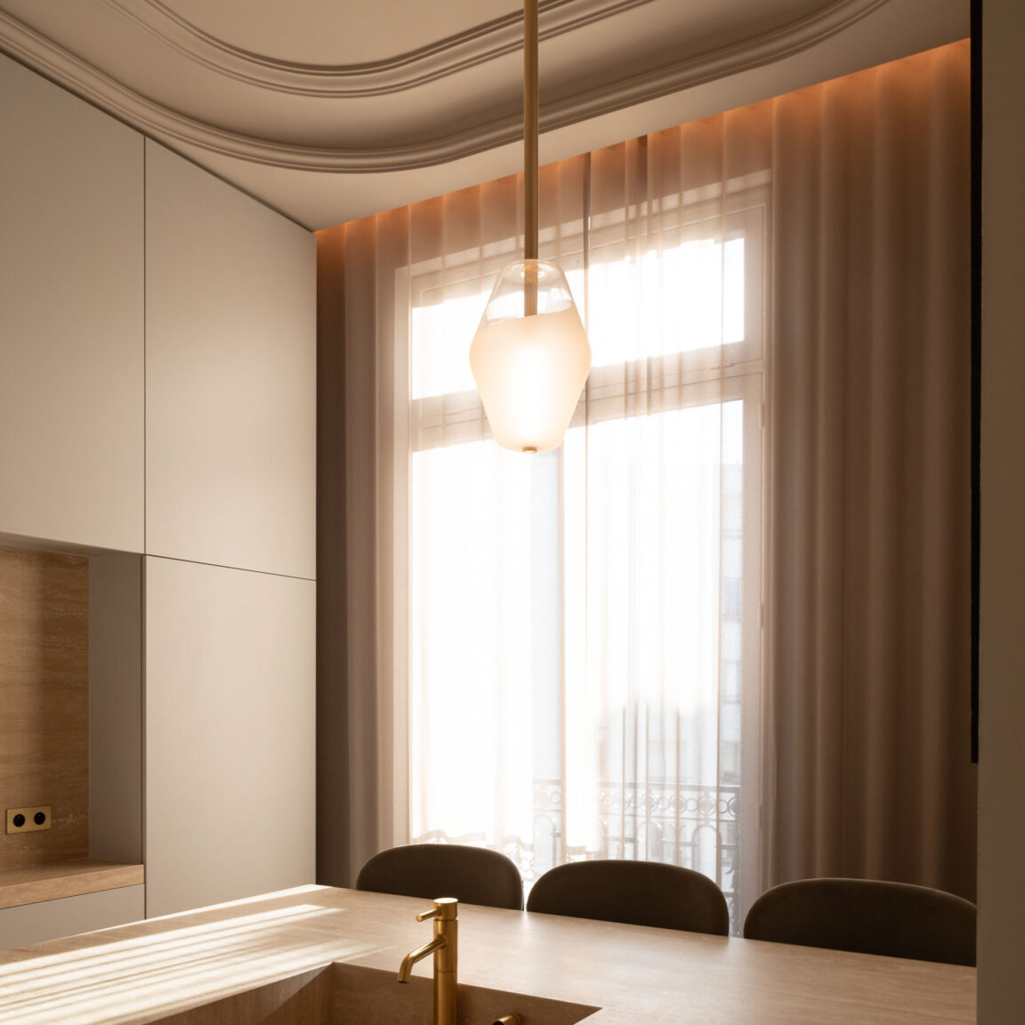 With its blown glass globe, Régis Botta's Rivoli pendant light hangs over the countertop of a warm and bright apartment