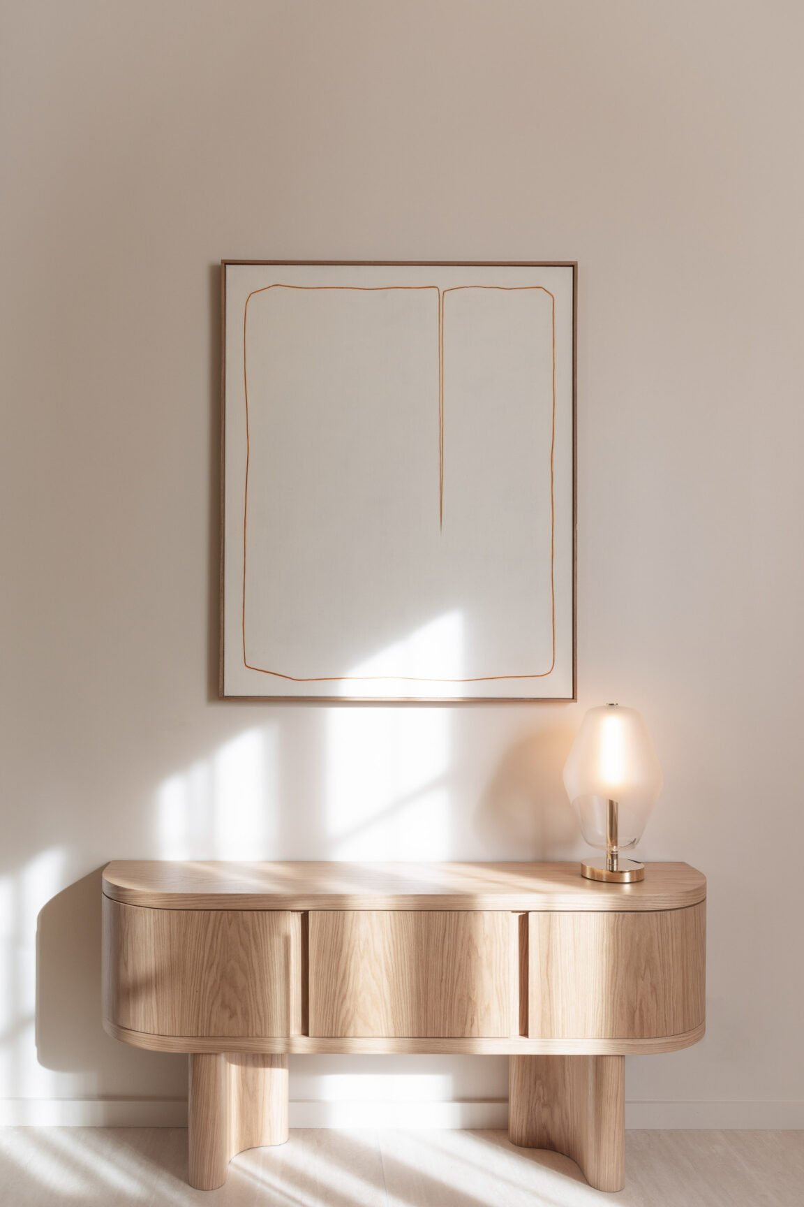 Auf einem Holztisch platziert beleuchtet die Tischleuchte Saint-Germain von Régis Botta ein minimalistisches Gemälde