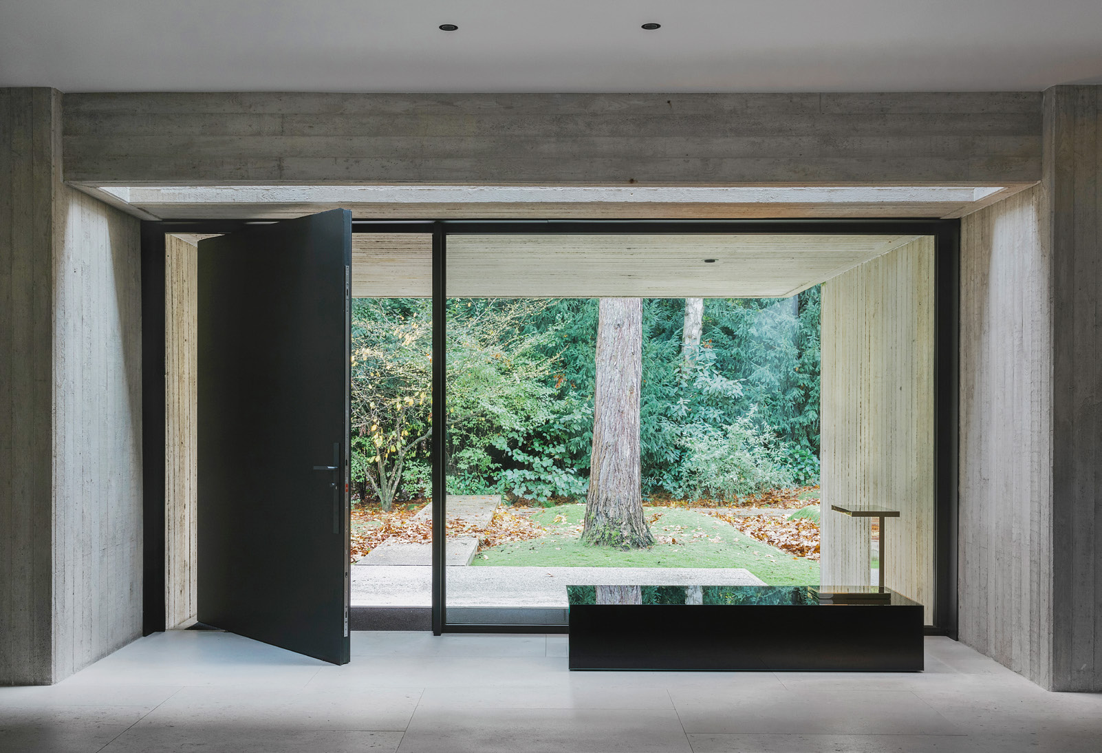 Black table with Furtiv LP table lamp and a large bay window overlooking a garden in the background