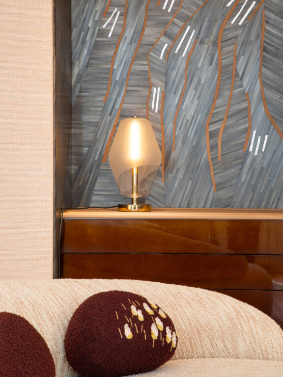 Saint-Germain table lamp with blown glass globe from Régis Botta's Les Parisiennes collection on a dresser in front of blue wallpaper