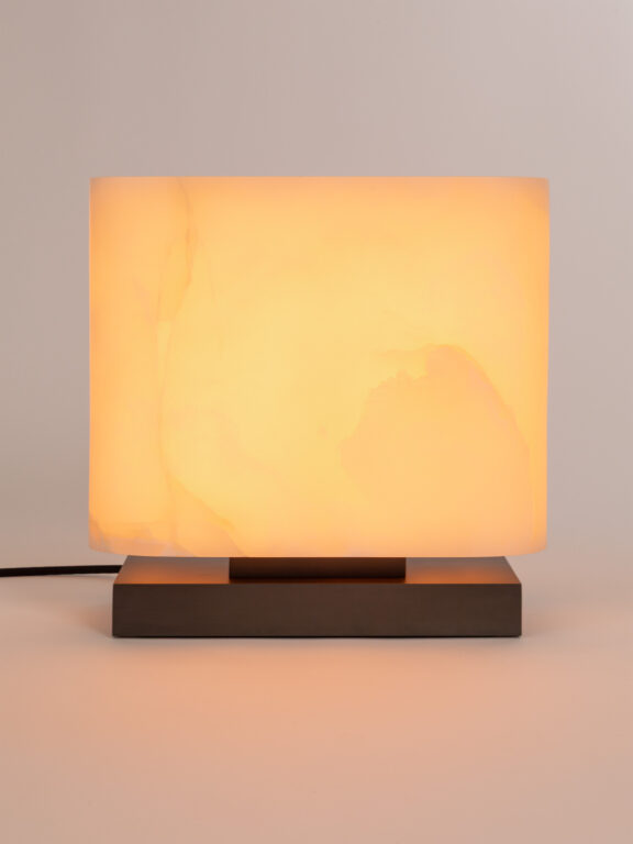 La lampe à poser Embrun LP diffuse une lumière chaude dans un espace blanc