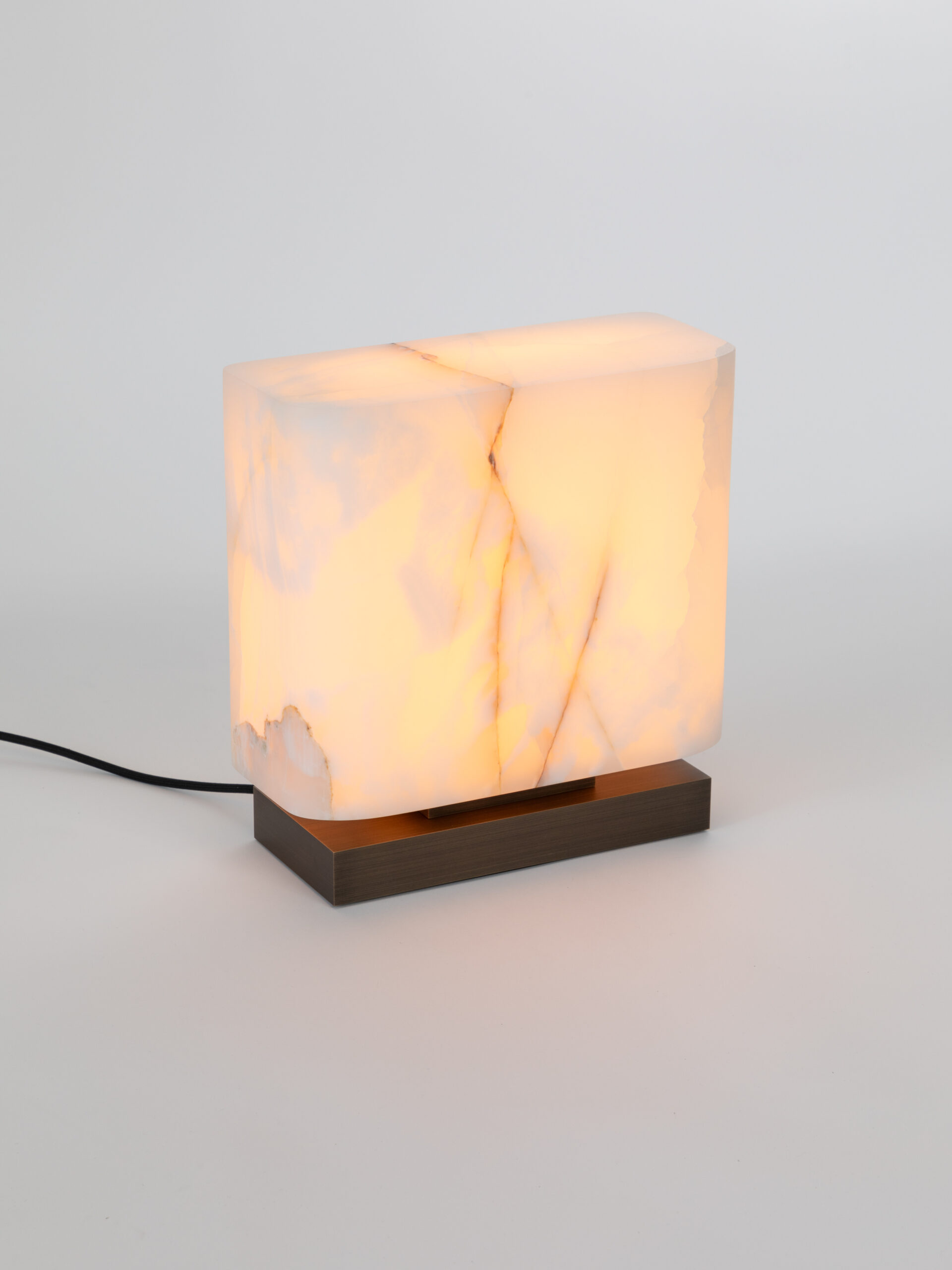 Lampe à poser Embrun LP en Onyx blanc et laiton sur un fond blanc