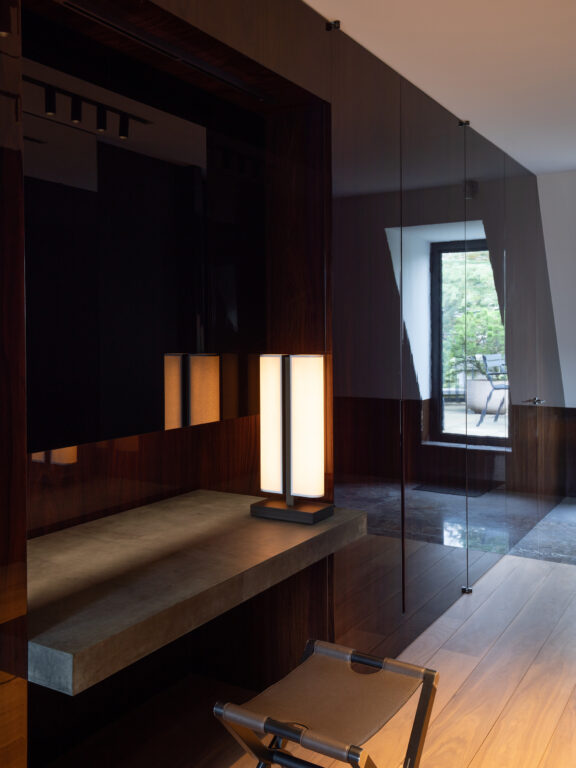 La lampe à poser Tennessee LP se reflète sur le mur sombre d'une villa.