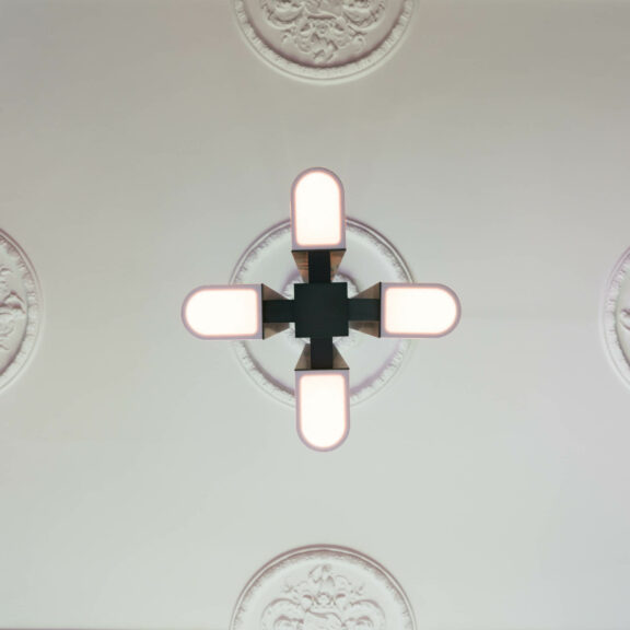 Low-angle shot of the four diffusers of the Tennessee S4 suspension fixture mounted on a white ceiling with moldings