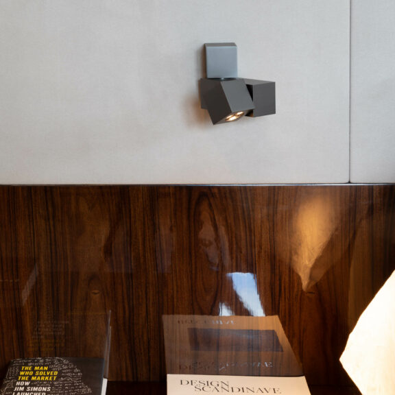 The Marienbad M wall lamp hangs on the wall like a bedside lamp, illuminating the book SCANDINAVIAN DESIGN.