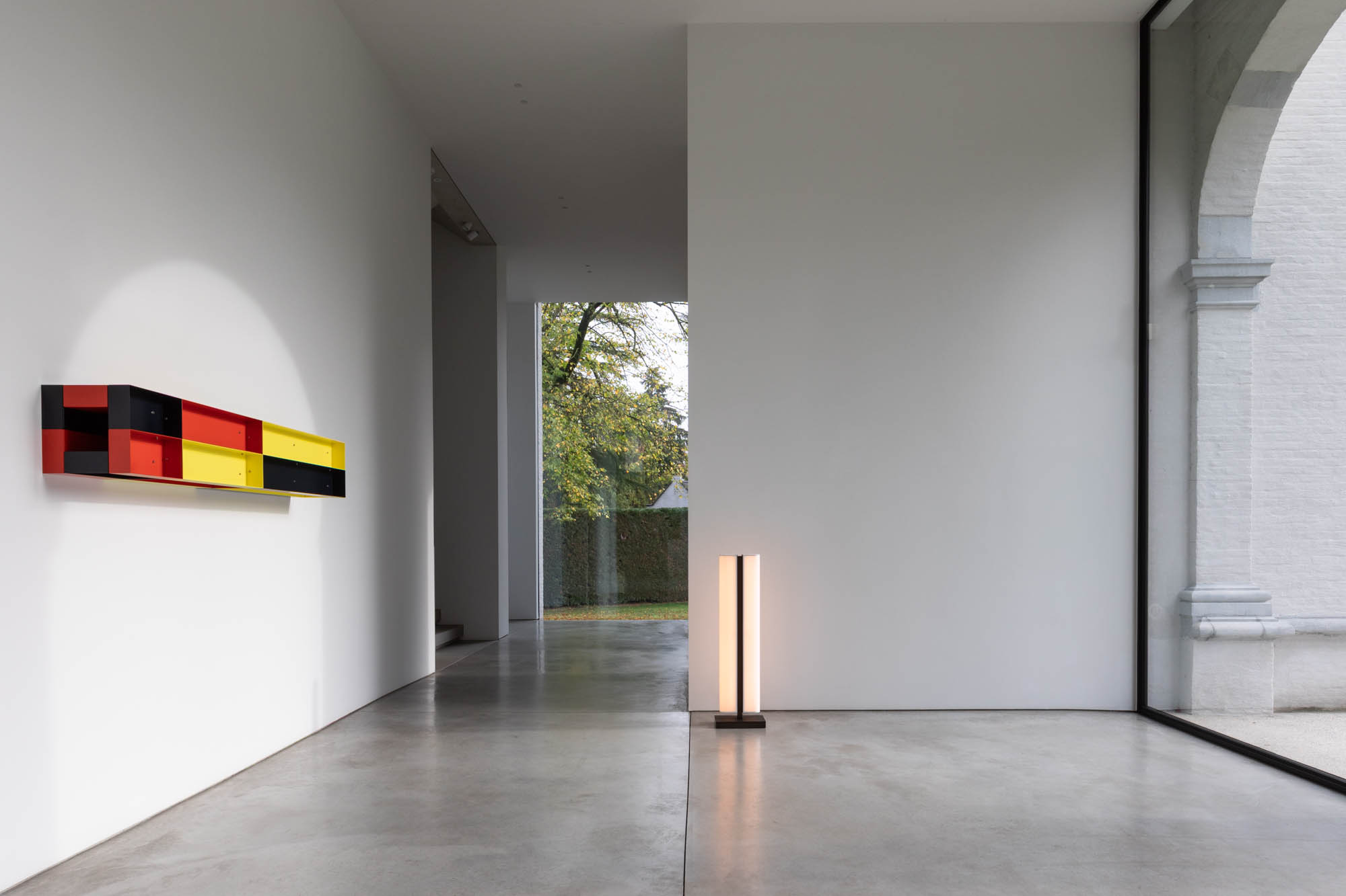 The Tennessee LH floor lamp illuminates a bright hallway with a colorful work of art on the wall.