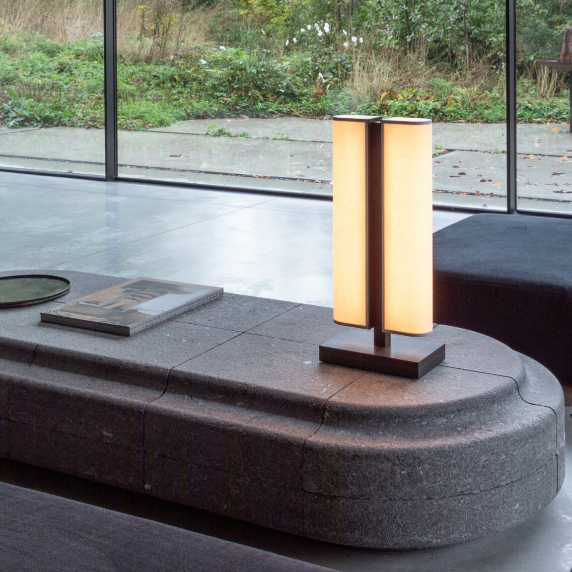 La lampe à poser Tennessee LP sur une table basse noire face à une baie vitrée