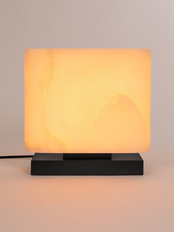 Die Tischleuchte Embrun LP verbreitet ein warmes Licht in einem weißen Raum.