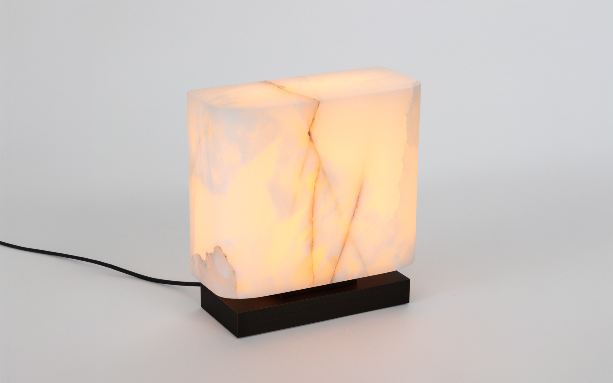 Lampe à poser Embrun LP en Onyx blanc et laiton sur un fond blanc