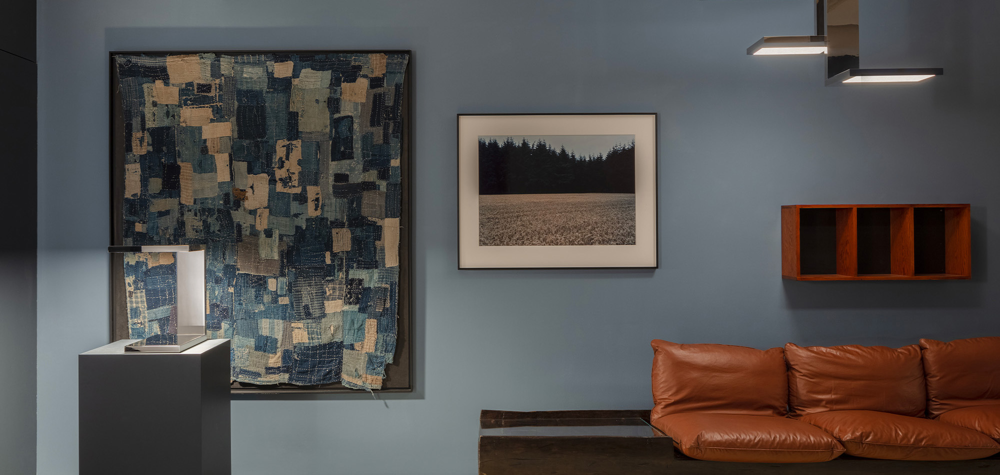 The Furtiv S pendant light and Furtiv LP table lamp illuminate a colorful living room with two large paintings.